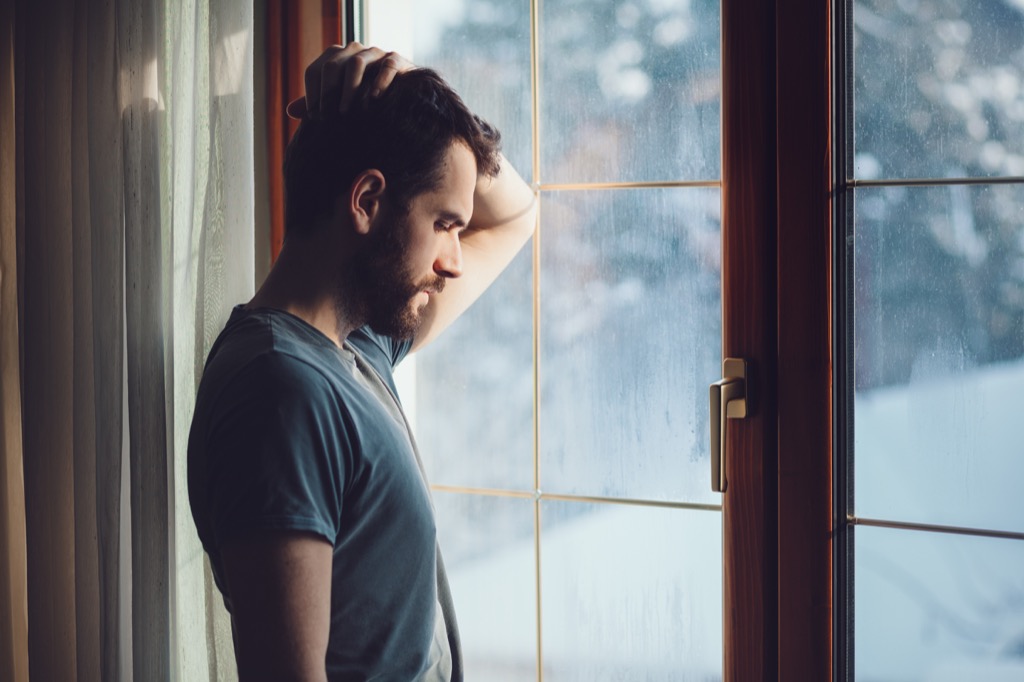 man looking out window thinking about riddle