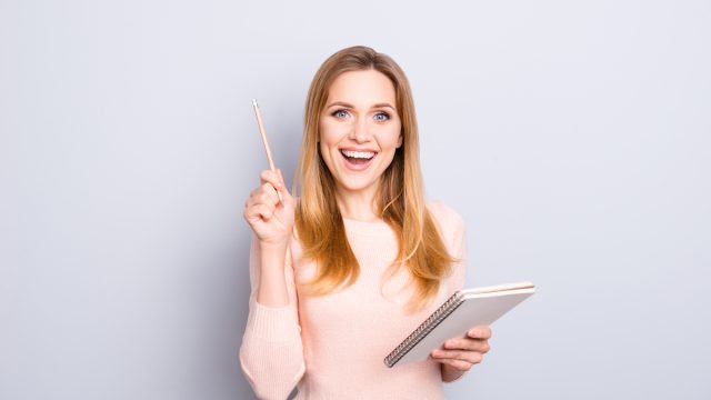 Smart woman holding pencil and notebook