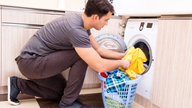 man putting clothes in washing machine laundry folding tips