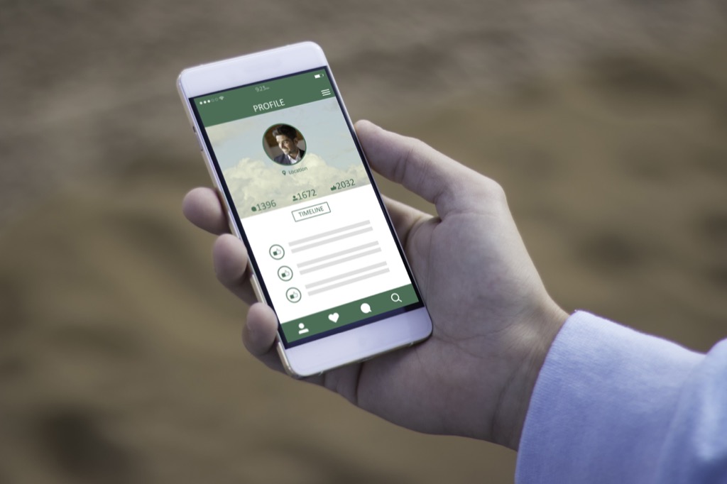 close up of hand holding phone with profile on screen