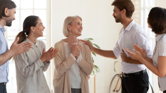 Older woman receiving compliments thankful to coworkers