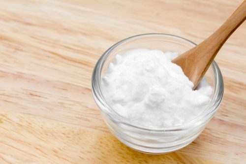 baking soda in glass bowl with wooden spoon