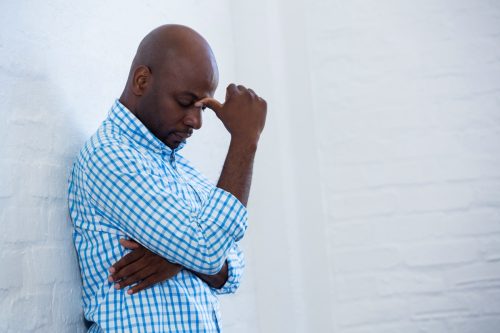 man upset, hangs head in hands