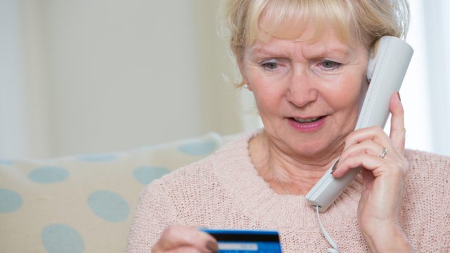 elderly woman giving credit card details by phone.