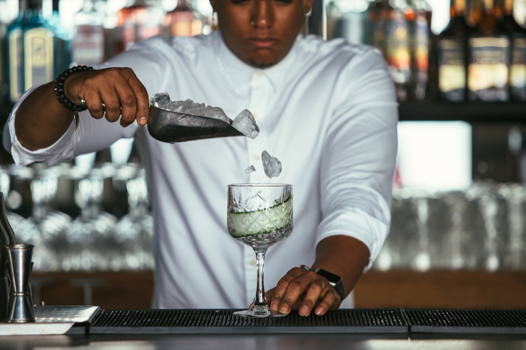 Man Pouring Ice Cubes in Glass Foods Doctors Avoid While Traveling