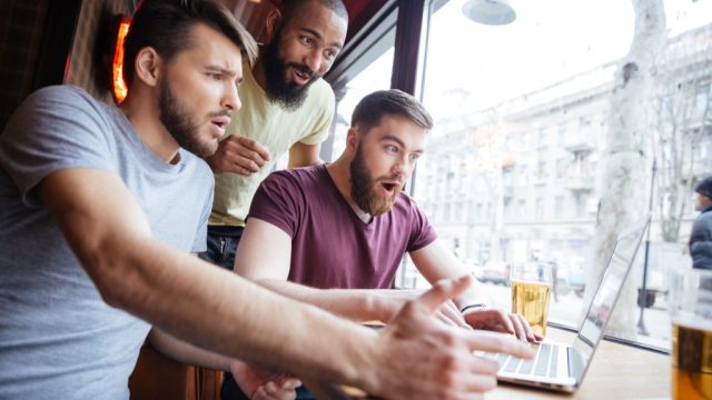 three guys look at a laptop