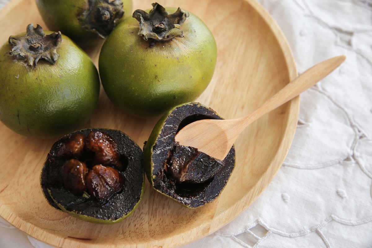 black sapote fruit with a wooden spoon in it