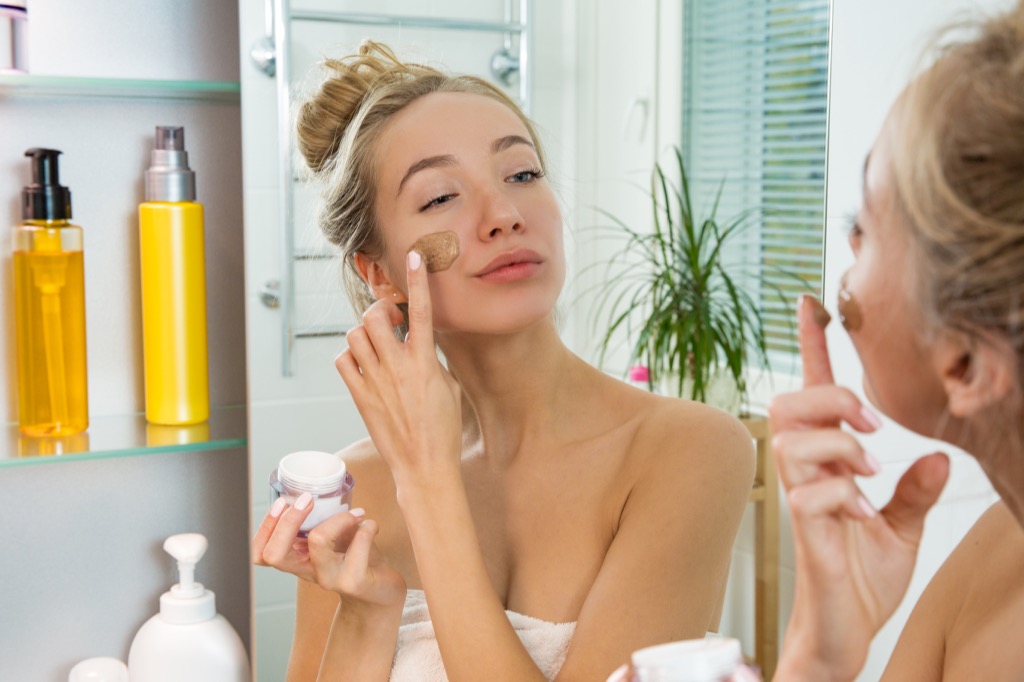 woman putting on makeup in mirror