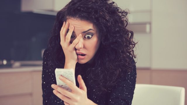 woman shocked surprised looking at phone
