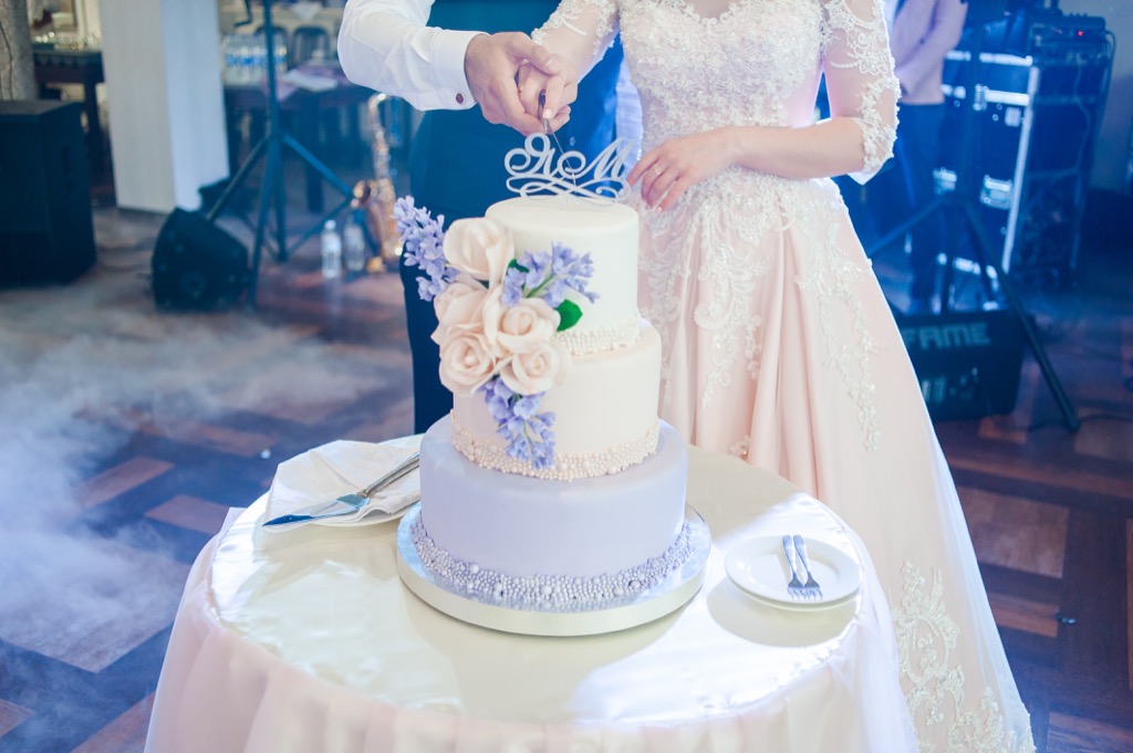 bride and groom cutting wedding cake 20 Old-Fashioned Wedding Traditions That Nobody Does Anymore