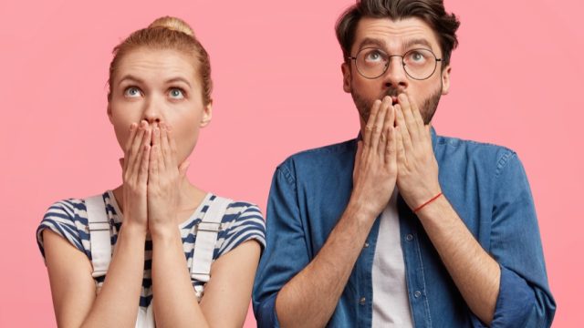 a shocked and surprised hipster couple against a pink background