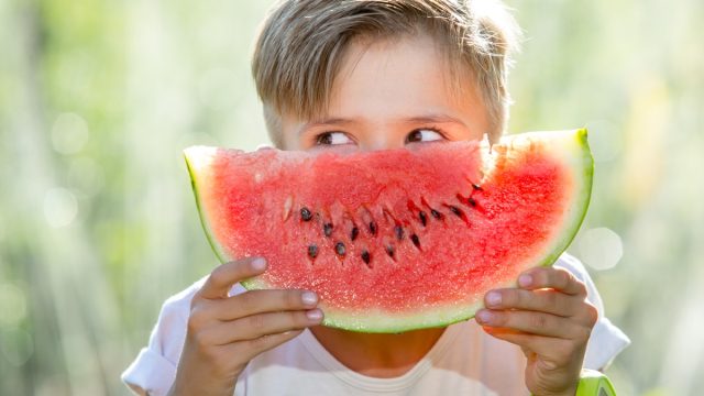 kid holding a watermelon in front of his face as if it is a smile, things you should never lie to kids about