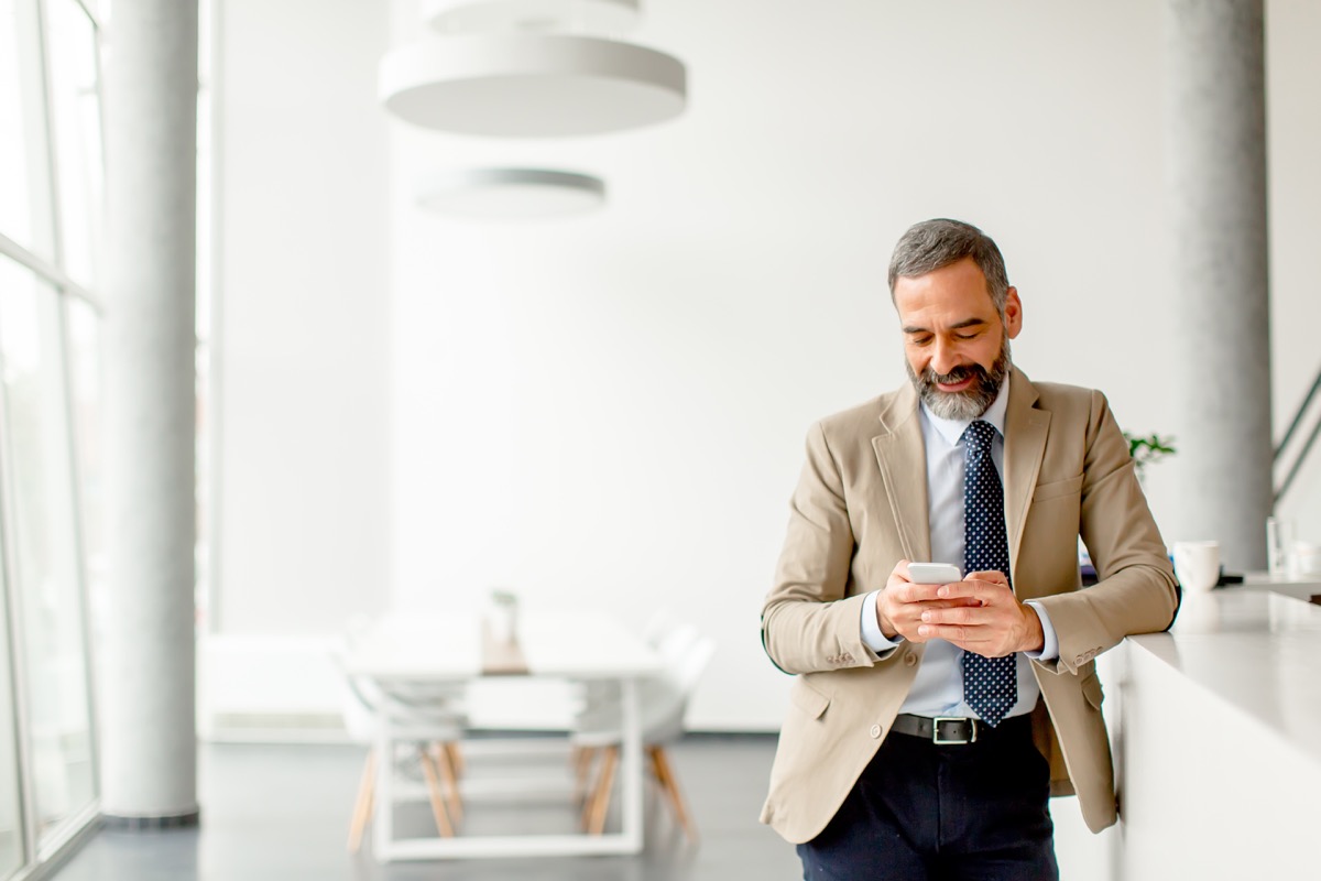 older man sending an email on phone