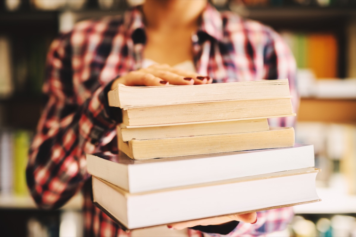 Close up of woman holding stack of books