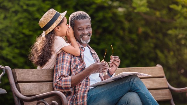 Granddaughter whispering secret to grandfather