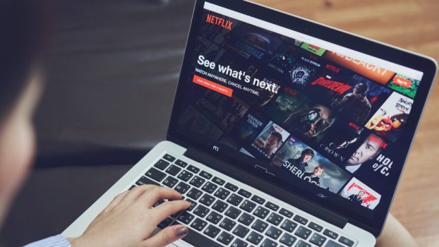 a man watching the best movies on netflix on his laptop