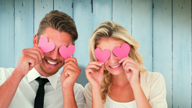 Man and woman holding cardboard cutouts over eyes