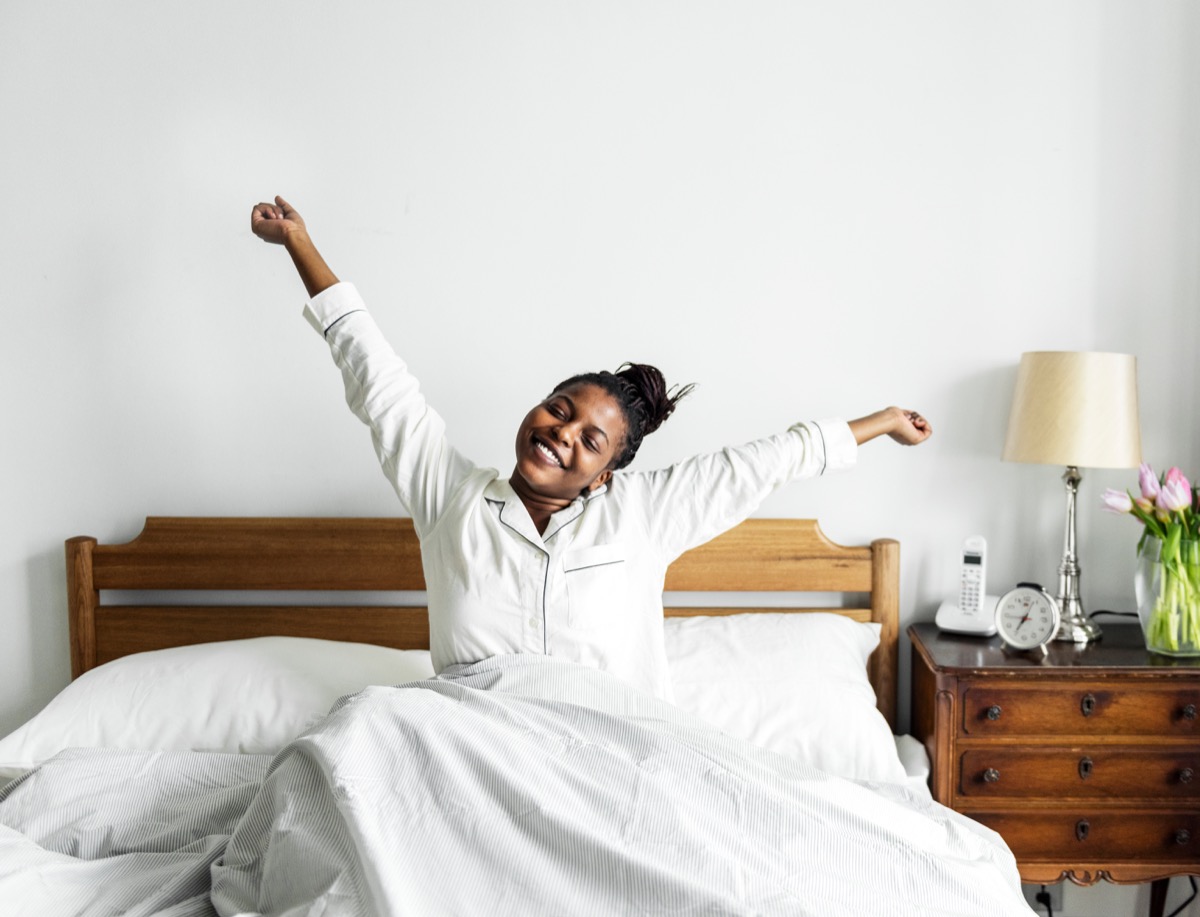 Woman stretching in bed after waking up
