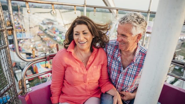 middle aged man and woman visit the fairground to enjoy the rides together