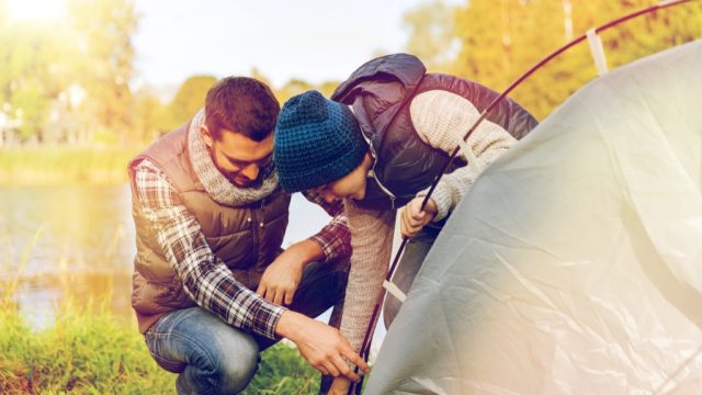 father and son setting up a tent
