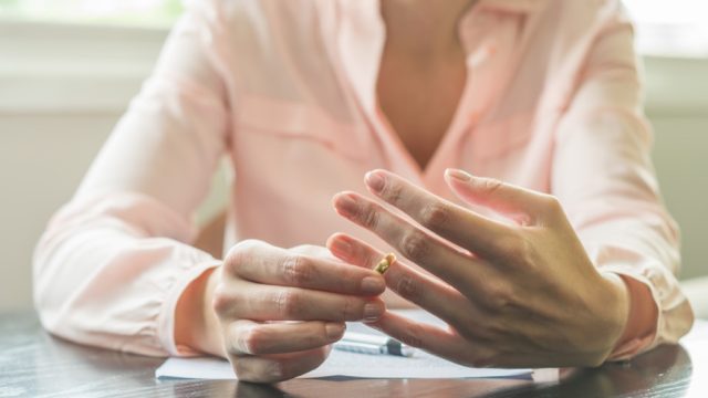 woman taking off a wedding ring sitting at a table going over divorce paperwork, bad parenting advice