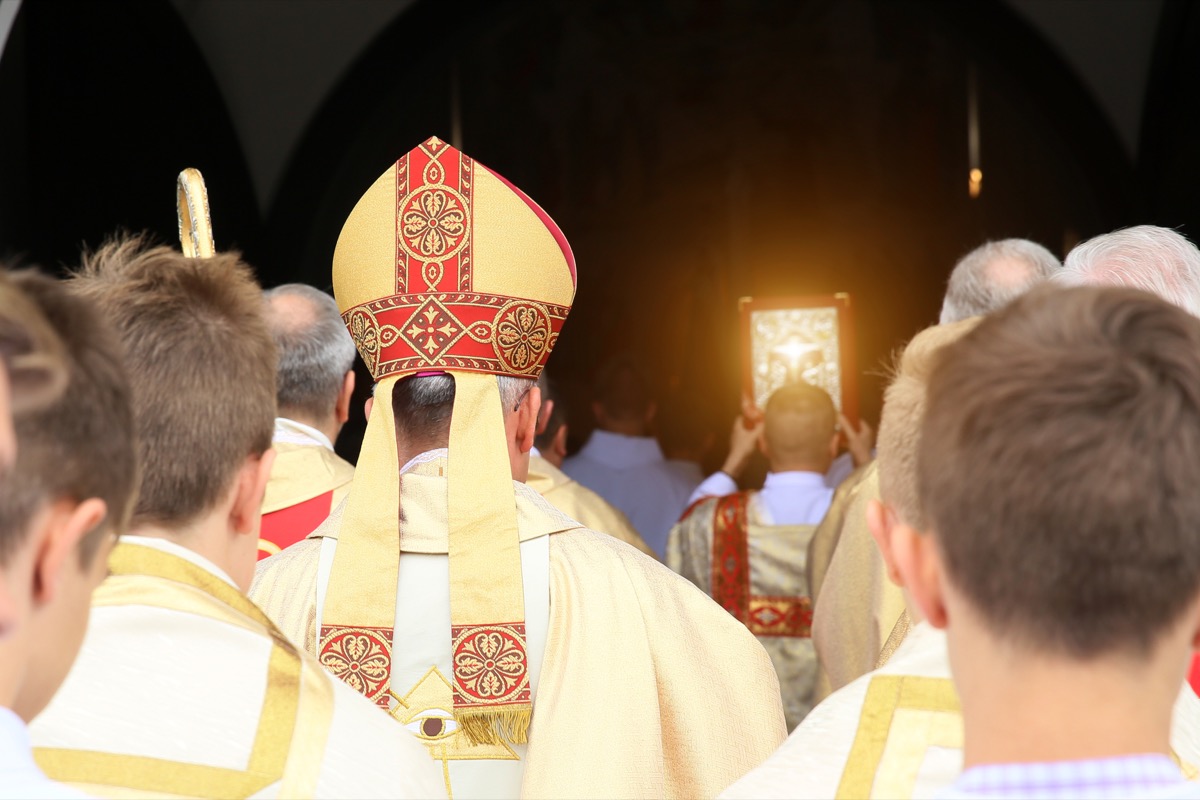 Bishop walks through a church followed by altar boys