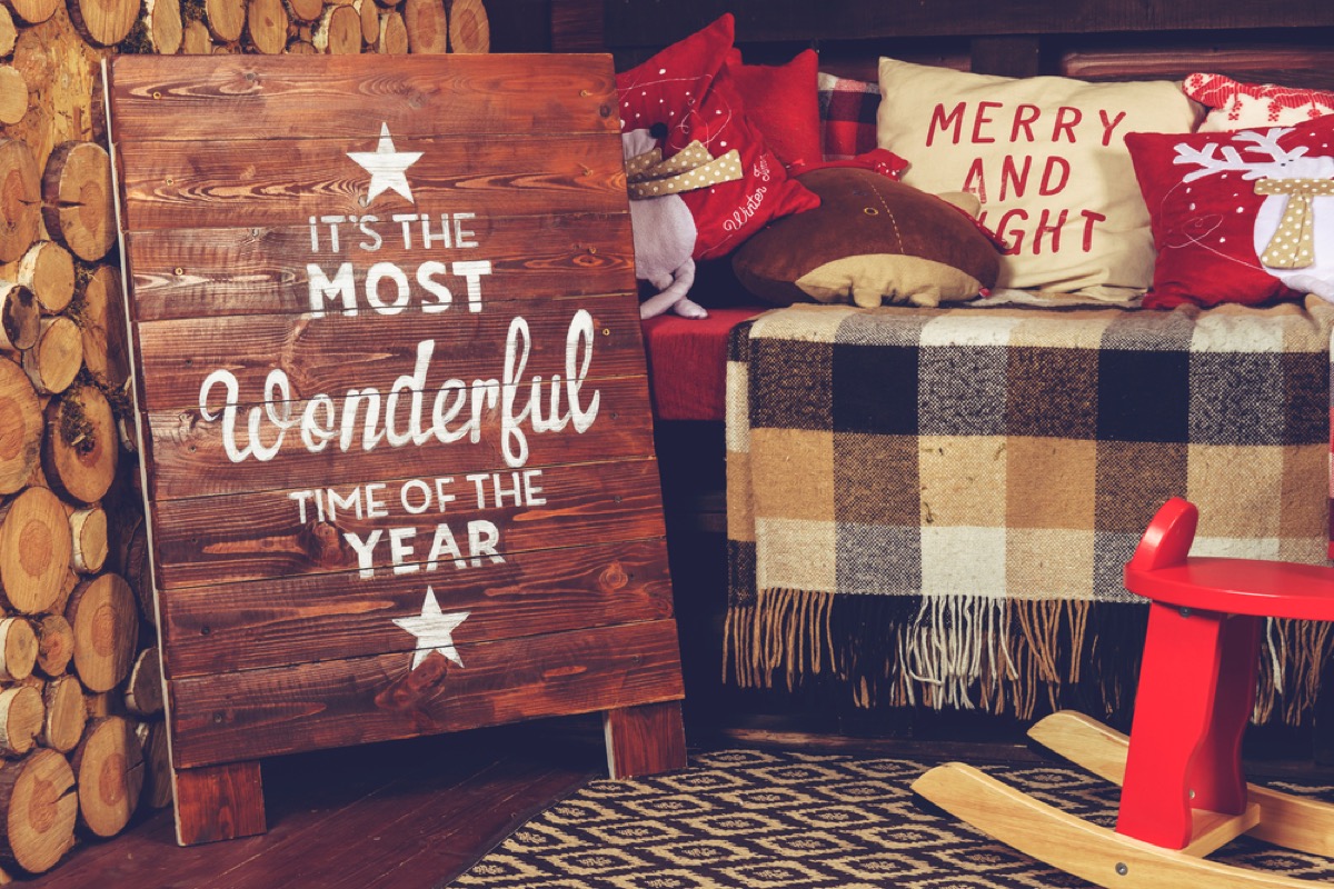 bench with plaid blanket and wooden sign in front of it reading "it's the most wonderful time of the year"