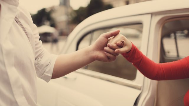 man helping woman out of her care in an old fashioned type photo
