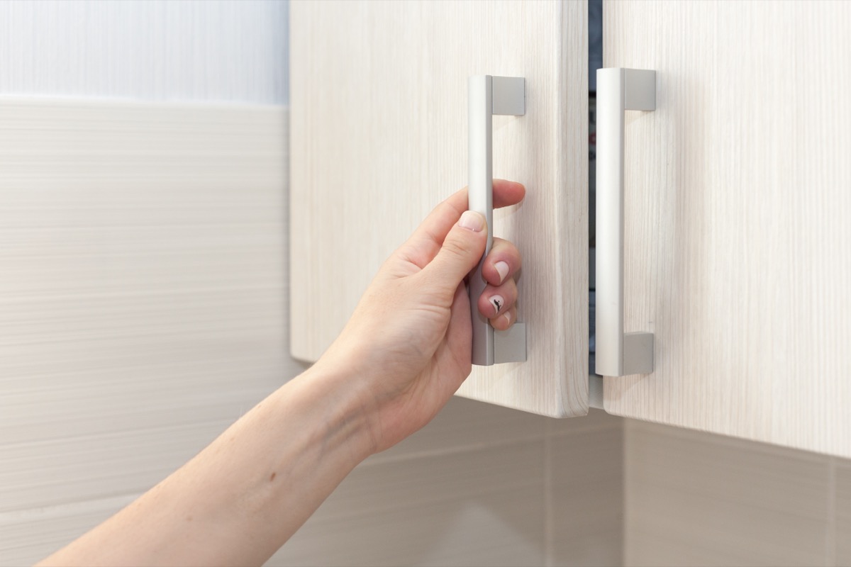 Person Opening a Kitchen Cabinet {How to Winterize a Home}