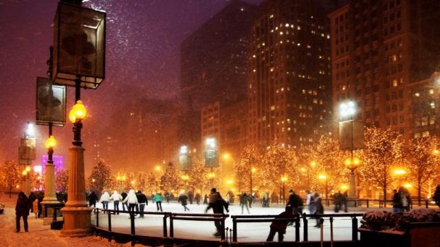 people ice skating in chicago during a snow storm at night