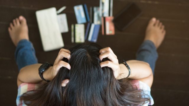 stressed woman staring at credit cards - paycheck to paycheck