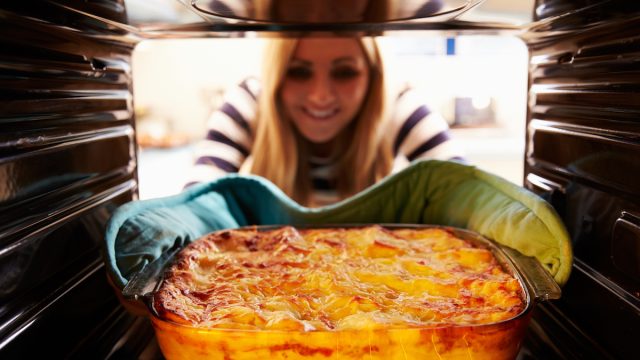 Woman taking a casserole out of the oven