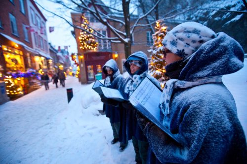 Parents, children, and grandfather singing carols for senior woman