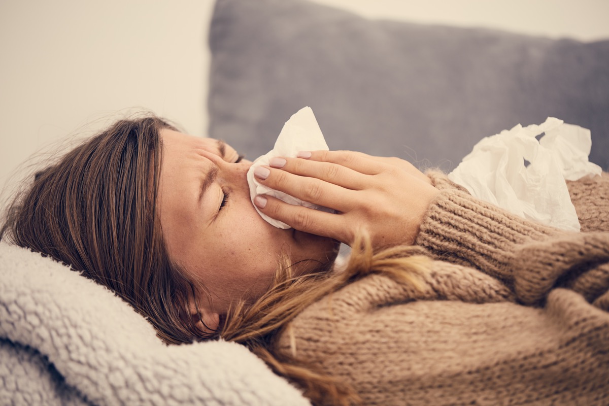 a sick woman on a coach blowing her nose with a tissue