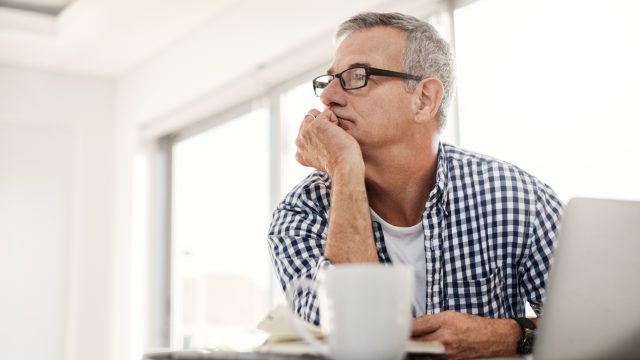 Shot of a mature man looking thoughtful while working on a laptop at home