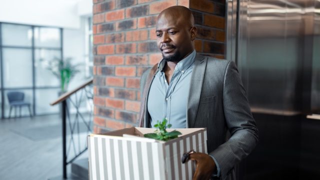 man leaving work with box after quitting job