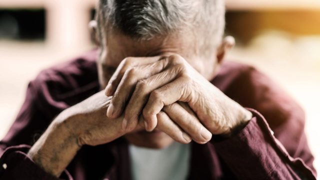 Sad older man with his head in his hand