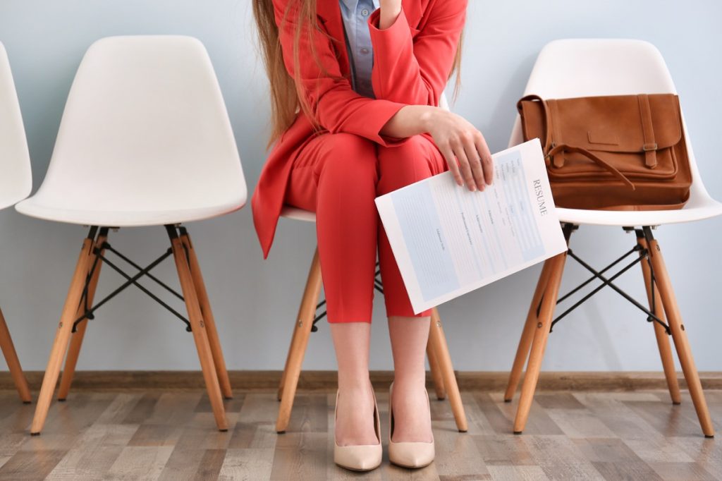 woman wearing a red suit waiting for an interview, holding her resume