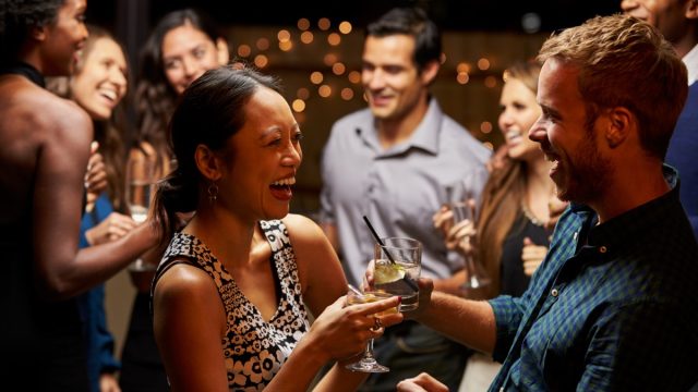 woman and man laughing in conversation at a cocktail party, bad jokes