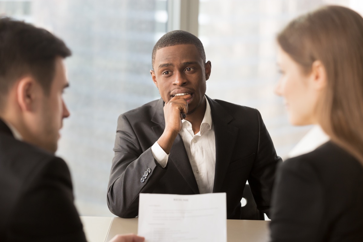 Man sitting across from man and woman hiring managers at job interview