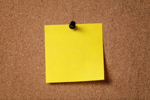 yellow post it note on cork board