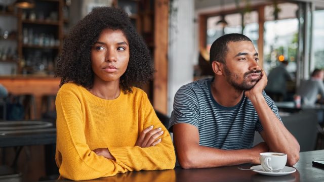 young black couple sitting next to each other at a coffee shop and not speaking or making eye contact