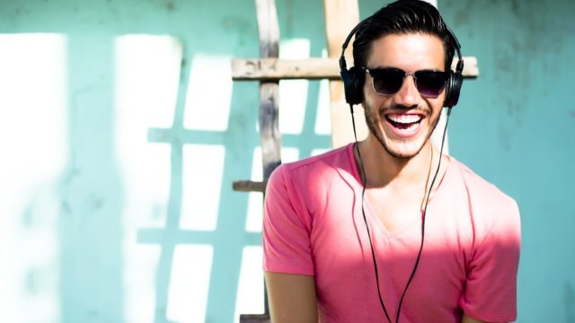 man wearing a pink shirt and laughing along to the funniest comedy podcasts