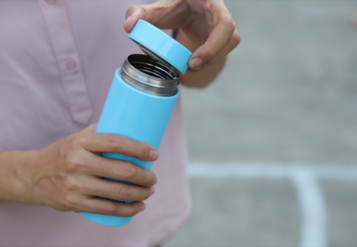 woman opens water bottle, which is gross and should be cleaned daily