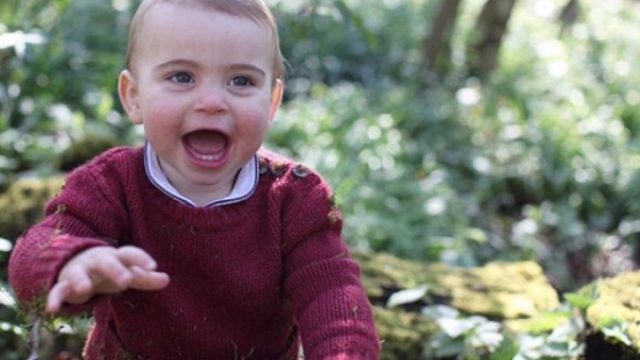 Prince Louis in maroon sweater sits in wooded area, official photo by Kate Middleton