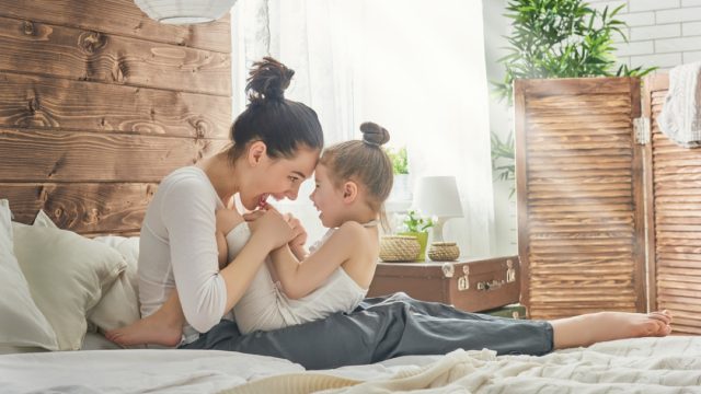 happy mother with child in bed, parenting myths