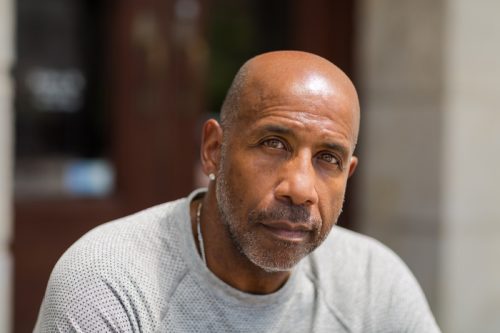 older man with light stubble wearing a gray shirt