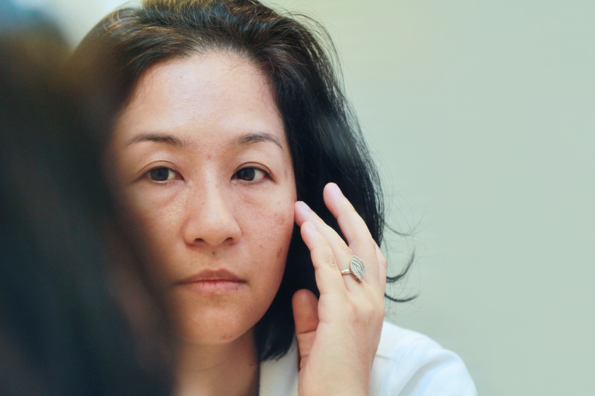 woman looking at her face in the mirror