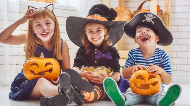 best halloween party games kids adults, kids sitting in costumes with pumpkins