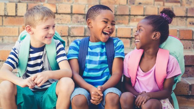 young kids with backpacks sitting outside talking, skills parents should teach kids